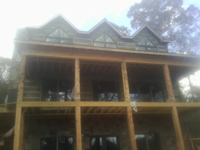 Dormers and porch framing on a large log home under construction — Roof Coating work by our crew in Amity