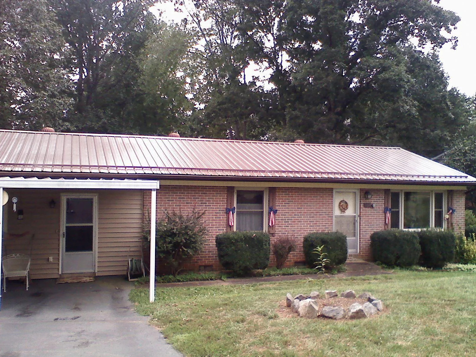 Bronze metal roof and carport on a brick ranch home — Roof Repair work by our crew in Amity